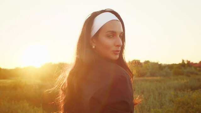 Woman with headband looking over shoulder at sunset. Golden hour photography. Mindfulness and serenity concept. Design for wellness blog, meditation guide.