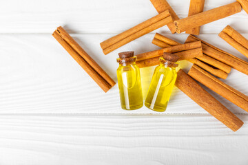 Cinnamon aromatic essential oil and cinnamon sticks on a wooden background. Aromatherapy. Organic cosmetic oil. Spa concept. Place for text. Copy space.