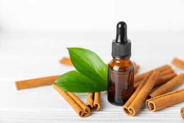Cinnamon aromatic essential oil and cinnamon sticks on a wooden background. Aromatherapy. Organic cosmetic oil. Spa concept. Place for text. Copy space.