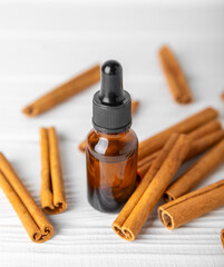Cinnamon aromatic essential oil and cinnamon sticks on a wooden background. Aromatherapy. Organic cosmetic oil. Spa concept. Place for text. Copy space.
