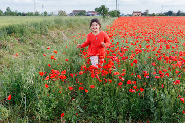 wide angle view of girl in red clothes running in the poppy field