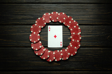 Red chips and ace of diamonds playing card on a black vintage table. Low key concept of luck or...