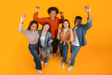 Friends with raised fists in excitement on orange background