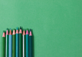 Green wooden colored pencils on the same background . Back to school. School supplies.