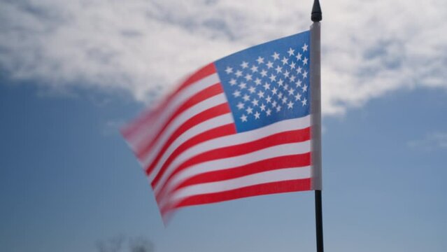 The American flag flutters in the breeze against the blue sky, symbolizing freedom and faith in one's beloved country.