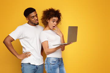 Shocked black millennial couple browsing on laptop