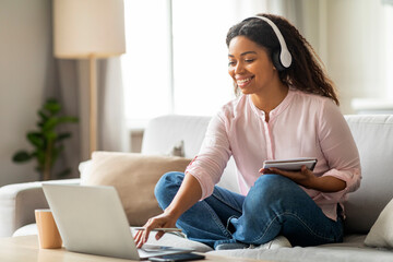 Lady with headphones looking at laptop, working online
