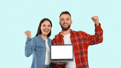 Couple with laptop celebrating victory on blue background