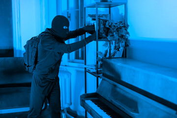 Burglar rummaging through a cabinet at night - obrazy, fototapety, plakaty