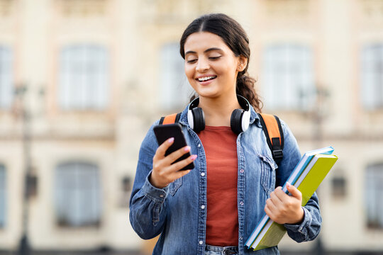 Indian lady student with headphones using smartphone