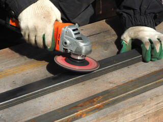 A worker processes metal with an angle grinder on a construction site.
The concept of locksmith work, processing of metal products.
