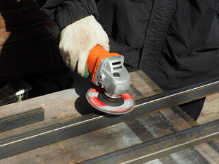 A worker processes metal with an angle grinder on a construction site.
The concept of locksmith work, processing of metal products.
