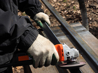 A worker processes metal with an angle grinder on a construction site.
The concept of locksmith work, processing of metal products.
