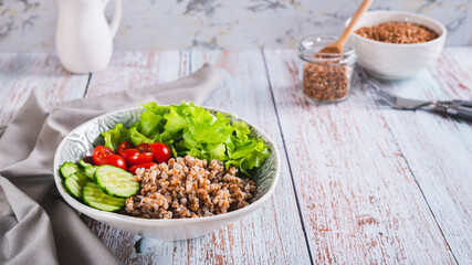 Bowl with buckwheat, cucumber, cherry tomato and lettuce on the table web banner