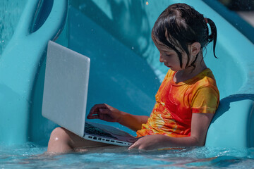 Learning and study everywhere and always. Young beautiful girl learning with laptop in the swimming pool water. Horiazontal image.