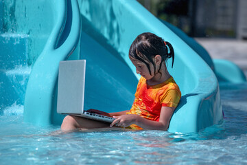 Learning and study everywhere and always. Young beautiful girl learning with laptop in the swimming pool water.