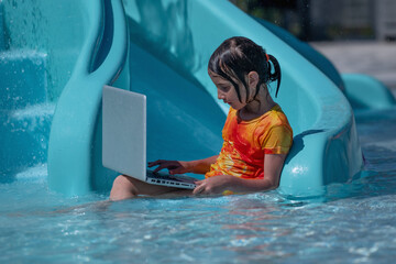 Learning and study everywhere and always. Portrait of young girl learning with laptop computer in the swimming pool water.