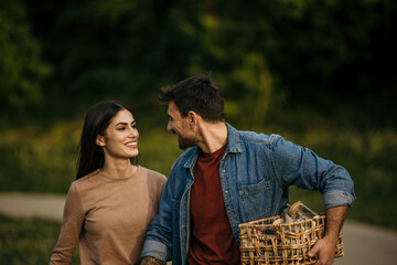 Fototapeta premium Affectionate couple walks through the park, ready for a picnic