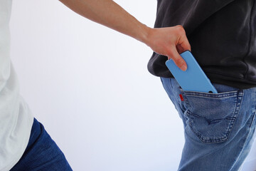 男性のジーンズのポケットからスマートフォン(携帯電話)を盗むスリ男 - obrazy, fototapety, plakaty
