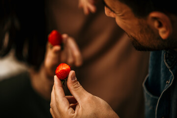 Close-up of a couple holding a fresh strawberrys and about to eat them