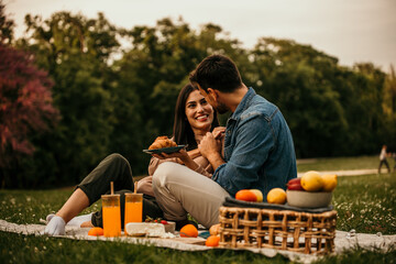 Affectionate couple laughing and enjoying snacks during a picnic outing