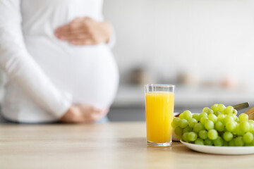 Pregnant woman with healthy food in kitchen