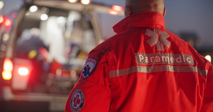 Back, man and paramedic walking to ambulance for emergency, ems service and healthcare in city. Rear view, medical professional and doctor outdoor at night for first aid, rescue operation and work