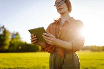 Smart farm. Woman Farmer with tablet in green field. Modern digital technologies. Agronomist at the...