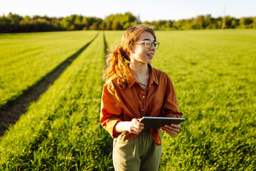 Smart farm. Woman Farmer with tablet in green field. Modern digital technologies. Agronomist at the...