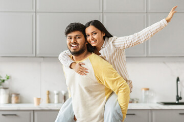 Happy Indian couple hugging in modern kitchen