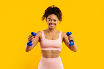Smiling african american woman exercising with dumbbells