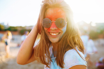 Happy woman covered in rainbow colored powder celebrating holi color festival. Young woman having...