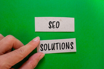 Seo solutions words written on paper pieces with green background. Conceptual symbol. Copy space.