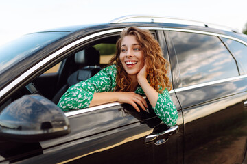 Happy woman while sticking out the car window enjoying travel. Freedom, rest, relax. Car travel.