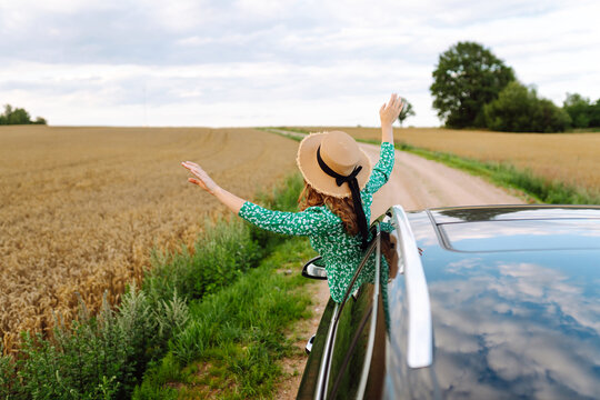 Happy woman while sticking out the car window enjoying travel. Freedom, rest, relax. Car travel.
