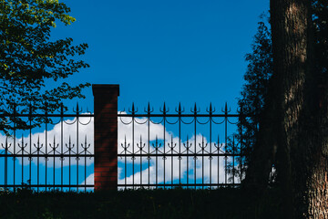 decorative wrought iron fence against a blue sky  - 784783070