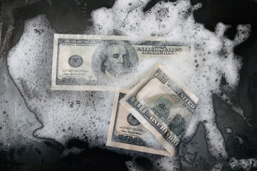 Two 100 dollar bills lies in foam on a baking sheet. View from above. Concept of money laundering,...