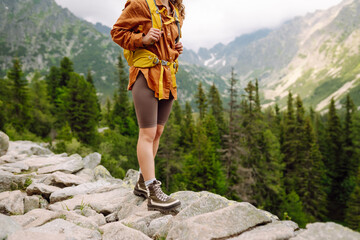 Close-up of female legs in hiking boots on a hiking trail, on top of a mountain outdoors. Travel,...