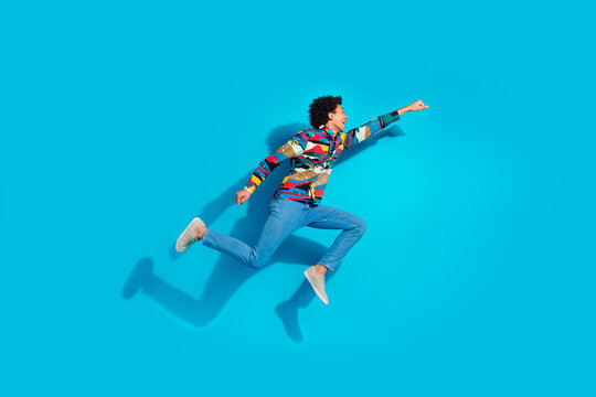 Full length photo of handsome young guy running flying superhero dressed stylish print garment isolated on blue color background