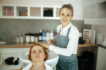 female hairdresser in modern beauty studio washing hair