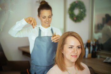40 years old woman hairdresser in beauty salon cutting hair - 784788870
