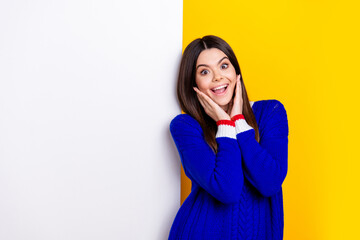 Photo portrait of pretty teen girl white empty space shocked wear trendy knitwear blue outfit isolated on yellow color background