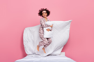 Photo of excited positive lady wear pajama embracing pillow jumping high isolated pink color...