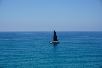  A Sailboat Sailing in the Middle of the Ocean. The boat is moving steadily through the water,...