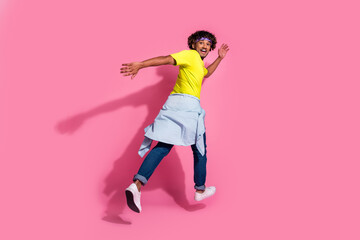 Fototapeta na wymiar Photo of crazy cool positive man wear trendy yellow clothes run away empty space isolated on pink color background