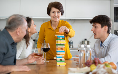 Smiling adult woman or Mother having fun enjoying tower building game with husband and adult...