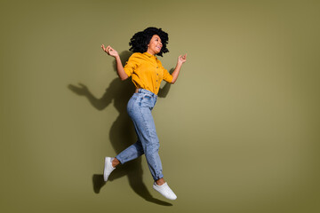 Full length portrait of pretty lady jumping empty space wear yellow shirt isolated on khaki color...