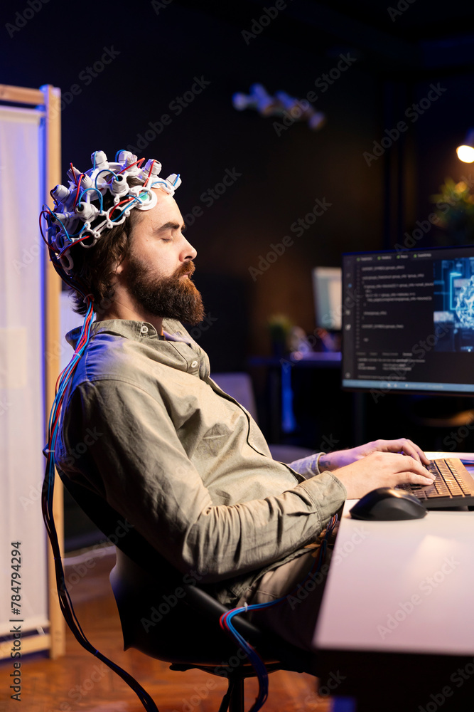 Poster man with eeg headset on typing on keyboard, writing code allowing him to transfer mind into computer