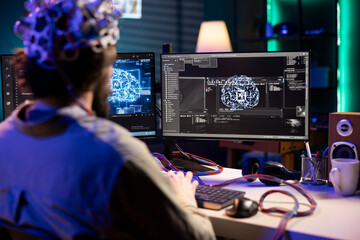 Software technician using EEG headset gear translating thoughts into PC commands using brainwave...