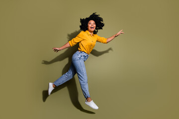 Fototapeta na wymiar Full length portrait of pretty lady jump rush empty space wear yellow shirt isolated on khaki color background